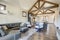 Beautiful large bright vaulted ceiling with large wooden beams and white walls living room interior with stone and leather sofa