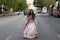 Beautiful Latin woman with long curly hair dressed in a 15th century dress running between cars on a big city avenue. The woman