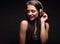 Beautiful laughing long hair young woman listening the music in wireless yellow headphone on dark black background