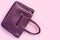 Beautiful leather purple handbags on pink paper background  in zine style