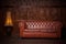 Beautiful leather sofa chester brown. In the interior of the loft of dark color, with a wooden wall in the background