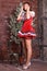 Beautiful legged redhead girl in red minidress and shiny stockings posing at the wall.