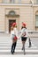 Beautiful leggy girlfriends in red berets are walking along a pedestrian crossing on the road, smiling and holding shopping bags