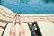 Beautiful legs, girls feet, women with red manicure on the backdrop of a deckchair and pool on a tropical warm exotic seaside