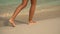 Beautiful legs of a young girl wolking on the beach