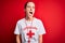 Beautiful lifeguard woman wearing t-shirt with red cross using whistle over isolated background angry and mad screaming frustrated