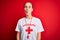 Beautiful lifeguard woman wearing t-shirt with red cross using whistle over isolated background making fish face with lips, crazy