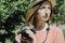 Beautiful lifestyle portrait of young adult woman with vintage film camera outdoors