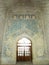 Beautiful light radiation from a large wooden door window and ancient colored tiles on the interior walls of the Soltanieh Dome.