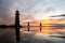 Beautiful lighthouse by sea golden hour sunset with reflection of people walking through sea ocean pools of water tide comes in