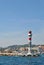 Beautiful lighthouse on the stone pier and cityscape at back, port of Marseille, France