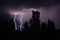 beautiful lightning during a thunderstorm at night in a forest that caused a fire, against a dark sky with rain