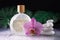 Beautiful lilac orchid flower and transparent bottle of perfume with white stones and monstera leaves on wet background