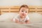 Beautiful little baby on the bed close-up and copy space. The ginger baby lies on his stomach and holds his head