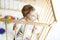 Beautiful little baby girl standing inside playpen. Cute adorable child playing with colorful toy