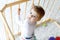 Beautiful little baby girl standing inside playpen. Cute adorable child playing with colorful toy