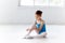 Beautiful little ballerina in blue dress for dancing puting on foot pointe shoes