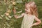 Beautiful little blonde girl tears green apples in the garden