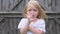 Beautiful little blue-eyed girl shows palm soiled in the sand