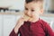 Beautiful little boy in the kitchen eating a piece of bread, hungry