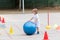 Beautiful little boy rolling the big blue ball on sports polygon