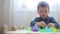 Beautiful little boy sculpts from green kinetic sand castles and shapes