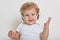 Beautiful little boy on white background with headphones, looking directly at camera with happy smile, showing hid teeth, wearing