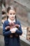 Beautiful little brunette girl with with pigtails, dressed in dark blue standing near mystic abandoned building with gothic stairs