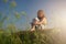 Beautiful little child girl sitting on a green meadow with a delightful view of the hilly landscape