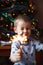 Beautiful Little child holding burning sparkler on New Year`s Eve, bengal fire. There is a background with multi colored lights