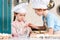 beautiful little children in chef hats and aprons cooking together