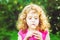 Beautiful little curly girl blowing dandelion, horizontal shot