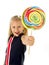 Beautiful little female child with sweet blue eyes holding huge lollipop spiral candy smiling happy