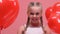 Beautiful little girl appearing behind red balloons, Valentines day surprise