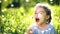 Beautiful little girl blowing dandelion at summer day.