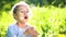 Beautiful little girl blowing dandelion at summer day.