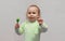 Beautiful little girl with brown eyes and a lollipop in her hands. Happy child in a green sweater eating a green lollipop candy,
