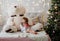 Beautiful little girl in a Christmas room drinking coffee in a bed with large Teddy bear plush toy