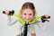 Beautiful little girl with curly hair in a light dress on a new bright bicycle. Shot on a light background