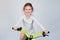 Beautiful little girl with curly hair in a light dress on a new bright bicycle. Shot on a light background