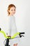 Beautiful little girl with curly hair in a light dress on a new bright bicycle. Shot on a light background