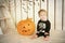 Beautiful little girl with Down syndrome sitting near a pumpkin on Halloween dressed as a skeleton