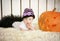 Beautiful little girl with Down syndrome sitting near a pumpkin on Halloween dressed as a skeleton