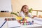 Beautiful little girl draws sitting at table