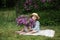 Beautiful little girl in dress with Lilac bouquet in garden. Spring blossom. Cute Smile young girl in straw hat with purple flowe