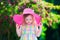 Beautiful little girl in a hat in blooming summer garden