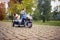 Beautiful  little girl having fun while driving electrical motorcycle with sidecar and her dog in park