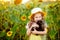 Beautiful little girl holds a black kitten in a field with sunflowers in summer