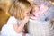 Beautiful little girl kisses the handle of her newborn sister lying in a basket