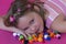 Beautiful little girl lying down on colorful pom poms